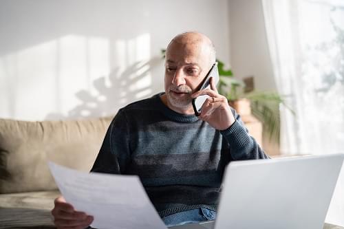 A person looking at a paper statement and talking on the phone