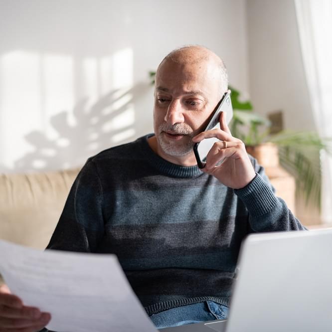 A person looking at a paper statement and talking on the phone