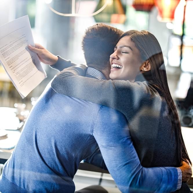 An excited couple hugging